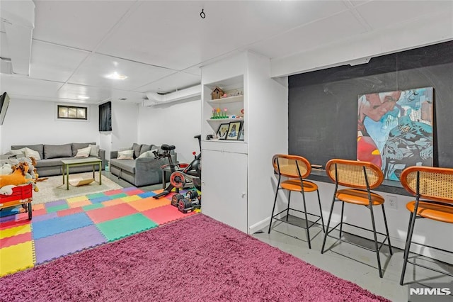 playroom with a paneled ceiling and concrete flooring