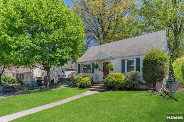 bungalow featuring fence, a playground, and a front lawn