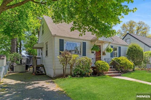 view of front facade featuring a shingled roof and a front yard