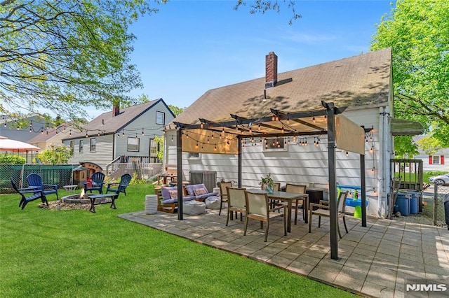 rear view of property with a lawn, a patio area, fence, a pergola, and a fire pit