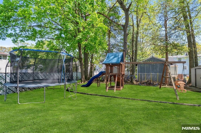 view of play area with a trampoline, fence, and a yard