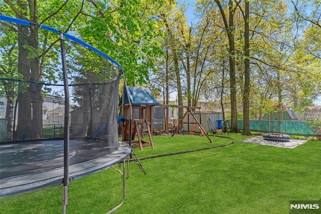 view of yard with a trampoline, a storage shed, a fenced backyard, a playground, and an outdoor fire pit