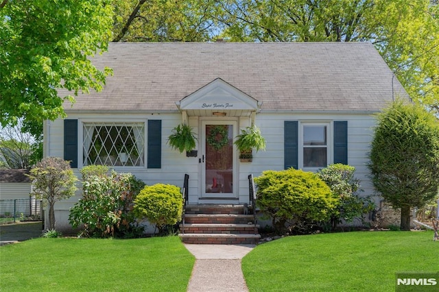 view of front facade featuring roof with shingles and a front lawn
