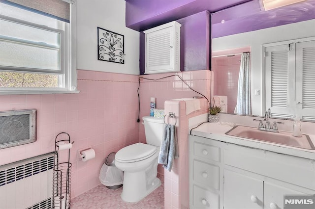 full bath featuring tile walls, a wainscoted wall, vanity, toilet, and radiator heating unit