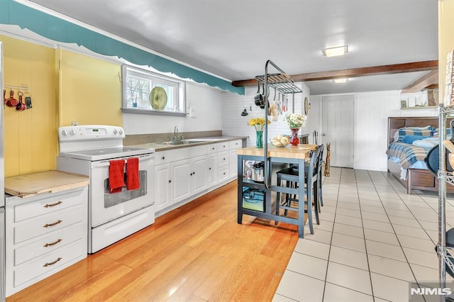 kitchen with a sink, stainless steel countertops, white cabinetry, light wood-type flooring, and white electric stove
