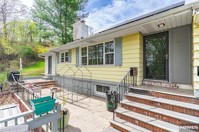 exterior space with entry steps, a patio, and a chimney