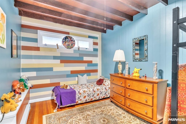 bedroom featuring wood finished floors and beamed ceiling