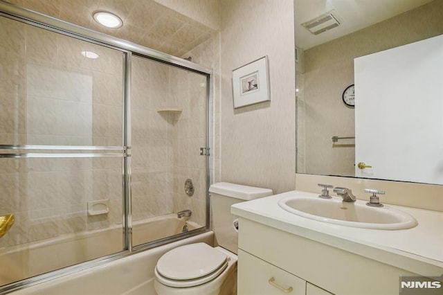 full bathroom with visible vents, bath / shower combo with glass door, toilet, and vanity