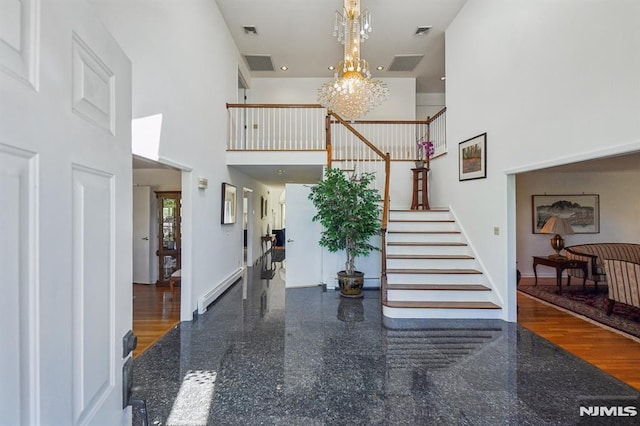 foyer with stairway, a high ceiling, granite finish floor, and a chandelier