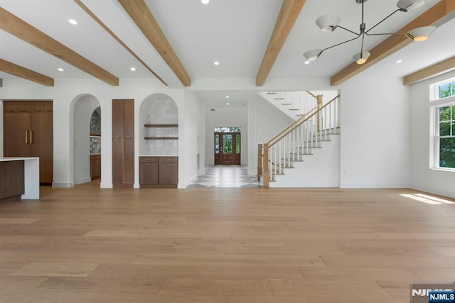229 Bogert Pl, Paramus, NJ 07652 - unfurnished living room featuring arched walkways, baseboards, light wood-type flooring, and beam ceiling