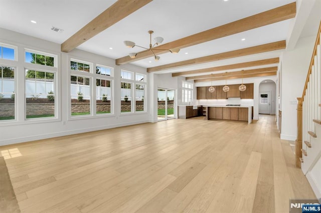 229 Bogert Pl, Paramus, NJ 07652 - unfurnished living room with an inviting chandelier, visible vents, beamed ceiling, arched walkways, and light wood finished floors