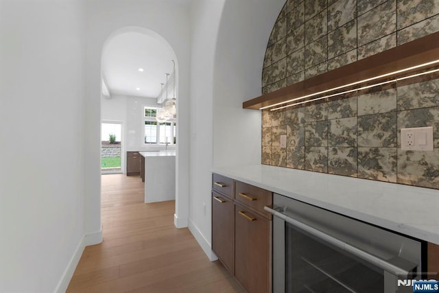 229 Bogert Pl, Paramus, NJ 07652 - bar featuring backsplash, beverage cooler, baseboards, and light wood-style flooring