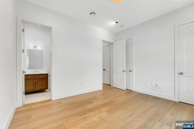 229 Bogert Pl, Paramus, NJ 07652 - unfurnished bedroom with light wood-type flooring, connected bathroom, baseboards, and visible vents