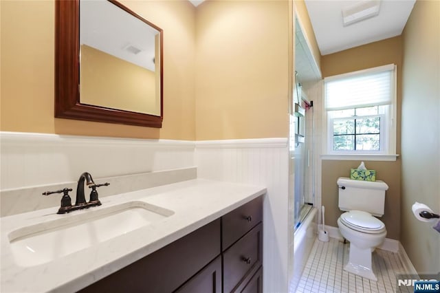 full bathroom featuring wainscoting, tile patterned flooring, vanity, toilet, and enclosed tub / shower combo