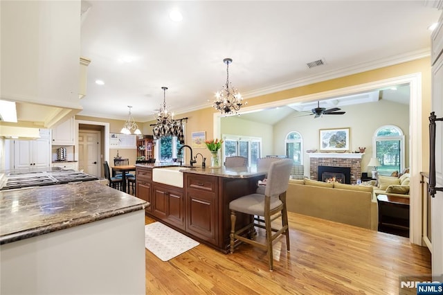 kitchen featuring a sink, a brick fireplace, ceiling fan with notable chandelier, and a wealth of natural light