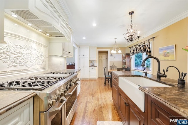 kitchen with custom exhaust hood, range with two ovens, a sink, light wood finished floors, and a notable chandelier