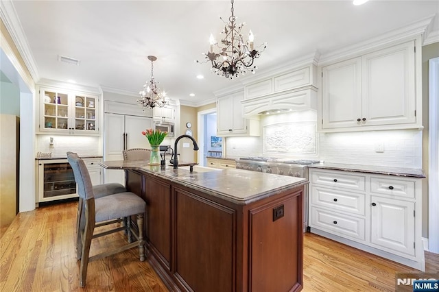 kitchen with appliances with stainless steel finishes, a sink, a chandelier, decorative backsplash, and wine cooler