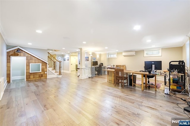 living room featuring crown molding, a wall unit AC, stairs, and light wood finished floors
