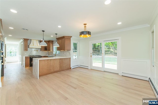 kitchen featuring range with gas stovetop, ornamental molding, a peninsula, custom exhaust hood, and light countertops