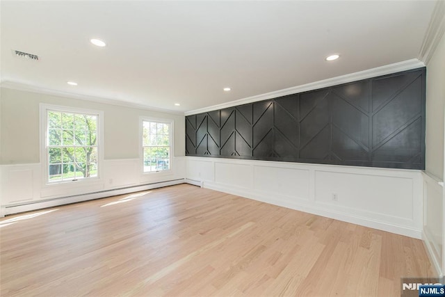 unfurnished room featuring baseboard heating, a decorative wall, wood finished floors, visible vents, and ornamental molding