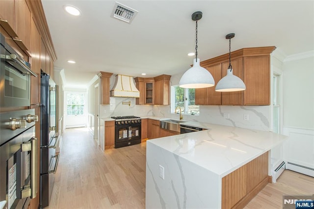 kitchen featuring a sink, a peninsula, high end black range oven, custom range hood, and visible vents