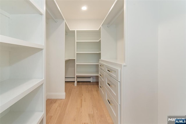 walk in closet with light wood finished floors and baseboard heating