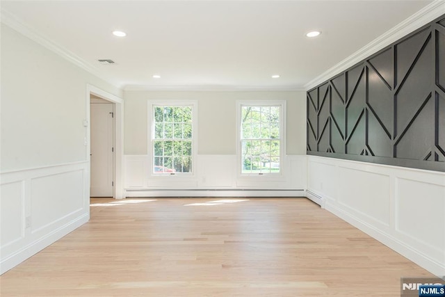 spare room featuring crown molding, light wood-style floors, and a decorative wall