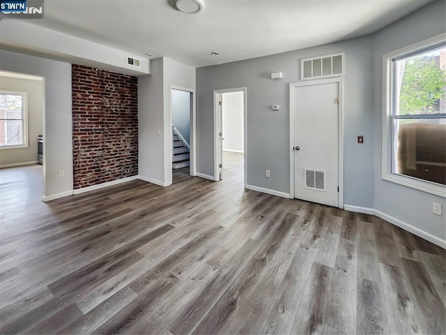unfurnished living room with visible vents, a wealth of natural light, and wood finished floors