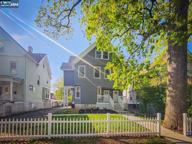 view of front of home with a porch, a front lawn, and a fenced front yard