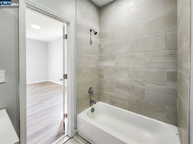 bathroom with baseboards, wood finished floors, and bathtub / shower combination