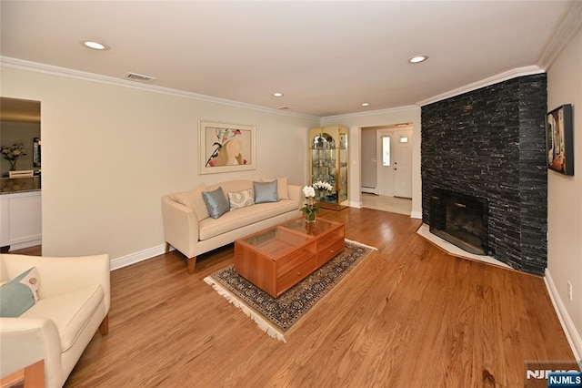 living room with visible vents, baseboards, crown molding, and wood finished floors
