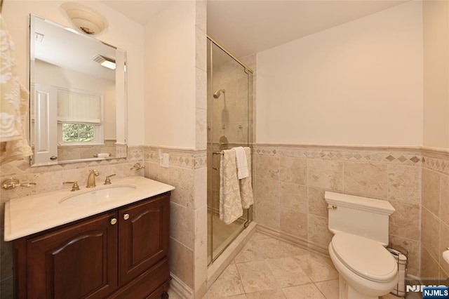 full bathroom with toilet, tile walls, wainscoting, and a stall shower