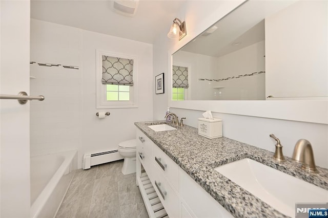 full bath with double vanity, a sink, a baseboard heating unit, and toilet