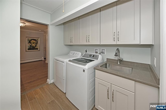 clothes washing area with cabinet space, independent washer and dryer, baseboard heating, a sink, and ornamental molding