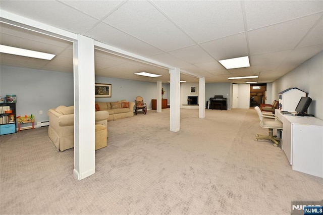 finished below grade area featuring carpet floors, a drop ceiling, and a baseboard radiator