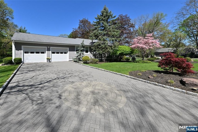 view of front of property featuring an attached garage, driveway, and a front lawn
