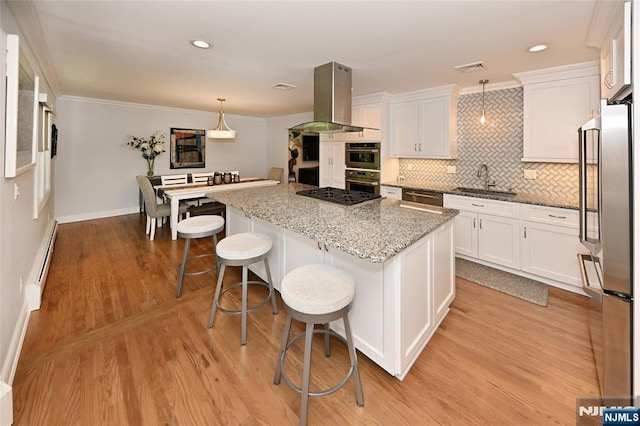 kitchen with baseboard heating, white cabinetry, stainless steel appliances, island exhaust hood, and a kitchen island