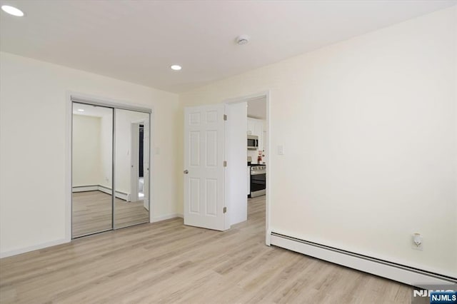 unfurnished bedroom with a closet, baseboard heating, recessed lighting, light wood-type flooring, and a baseboard radiator