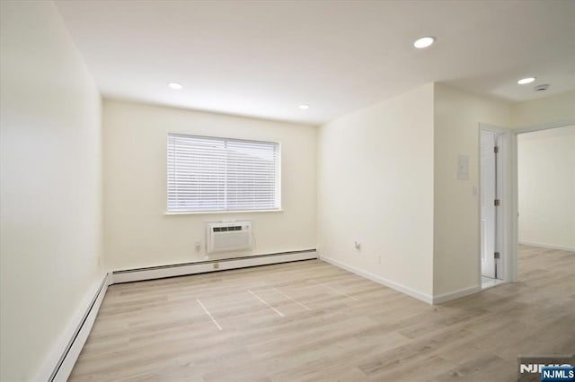 spare room with light wood-style floors, baseboards, baseboard heating, and an AC wall unit