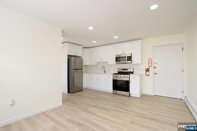 kitchen featuring a sink, light countertops, white cabinets, light wood-style floors, and stainless steel appliances