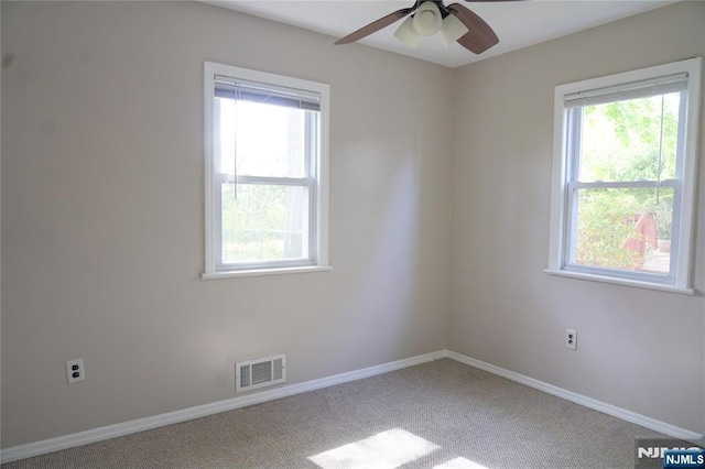 unfurnished room with baseboards, ceiling fan, carpet, and visible vents