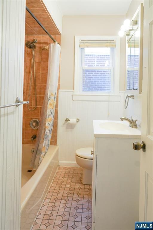 full bath with a wainscoted wall, vanity, toilet, and shower / tub combo
