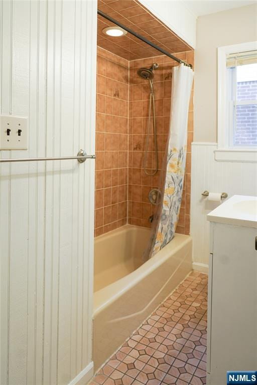 bathroom with vanity, tile patterned flooring, a wainscoted wall, and shower / bath combination with curtain
