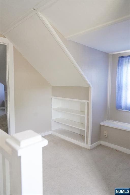bonus room featuring built in features, baseboards, carpet, and lofted ceiling