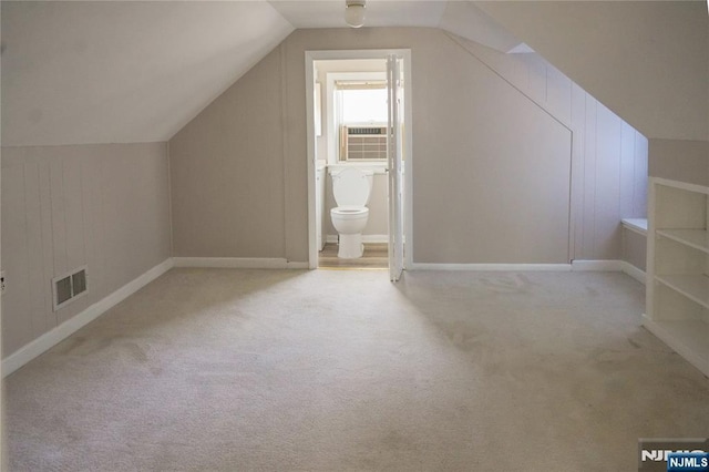 additional living space with visible vents, baseboards, cooling unit, lofted ceiling, and carpet