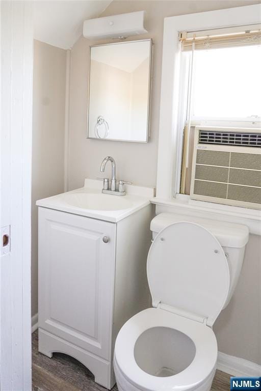 half bathroom with vanity, baseboards, lofted ceiling, and toilet