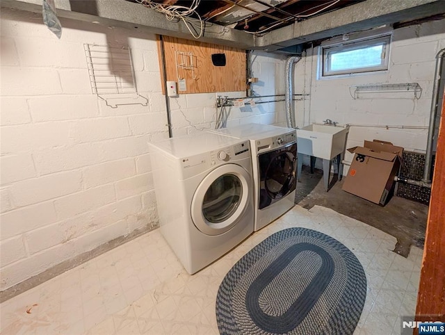 laundry area with independent washer and dryer, laundry area, a sink, and light floors