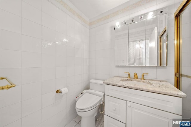 bathroom featuring toilet, tile walls, and vanity