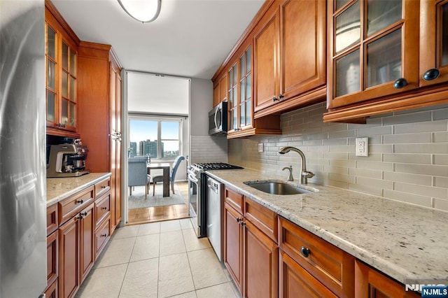 kitchen with a sink, decorative backsplash, brown cabinets, and stainless steel appliances