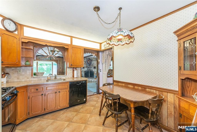 kitchen featuring a sink, a wainscoted wall, wallpapered walls, tasteful backsplash, and black appliances